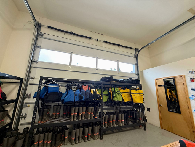 Rows of rain boots and life jackets and dry bags for client use on tours.