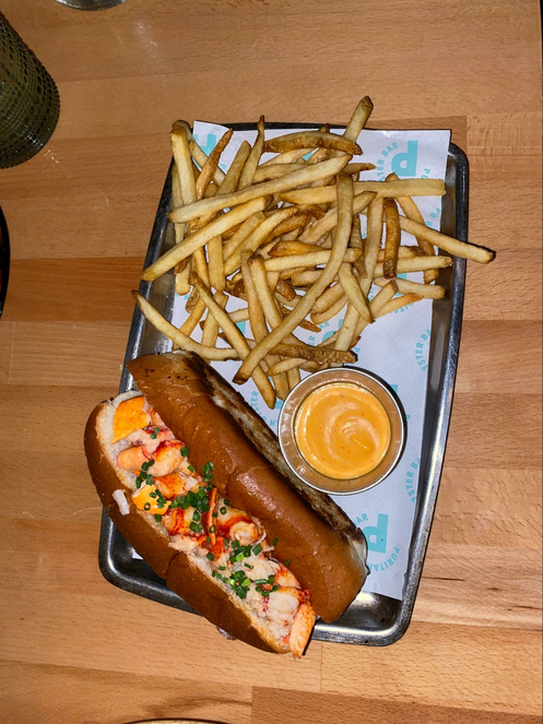lobster role piled high with lobster on a tray with a side of french fries. 