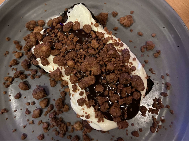 chocolate cheesecake topped with whipped cream, chocolate sauce and chocolate crumbles.