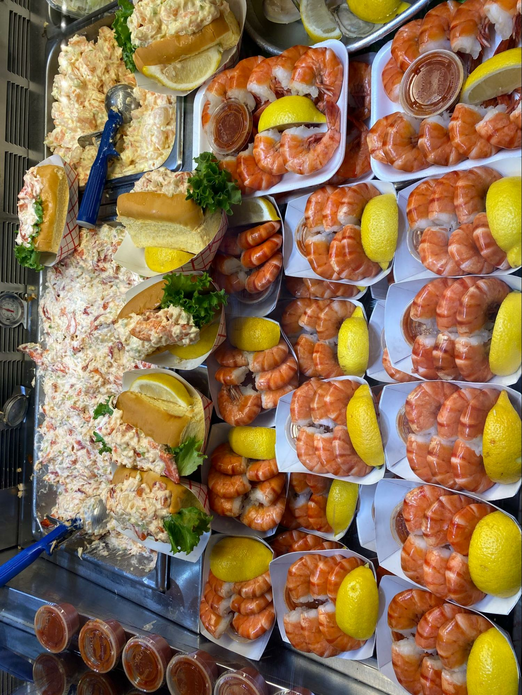 trays of fresh shrimp with lemon along with lobster rolls.