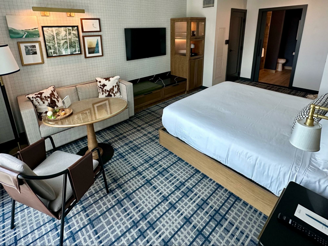 King room at the Omni PGA Resort in Frisco, Texas, features a blue and gray plaid rug, loveseat with cowhide throw pillows and golf-themed artwork on the walls and is a good destination for a sports trip.