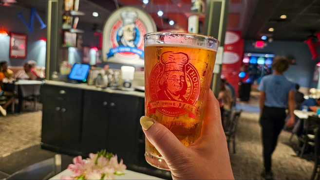 A beer being held in front of the logo in the restaurant Food for Thought