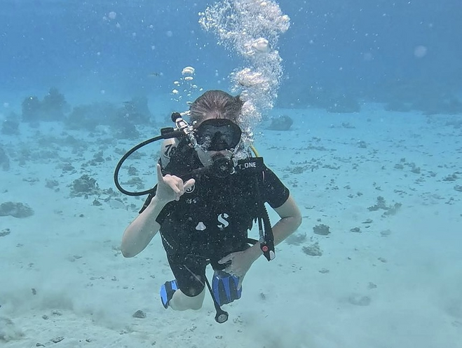 A female scuba diver swims and blows bubbles while under the water off the coast of Tahiti Nui in French Polynesia.