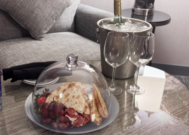 A charcuterie plate under a glass dome, a bottle of wine and two glasses, served at the Hyatt Regency in Boston.