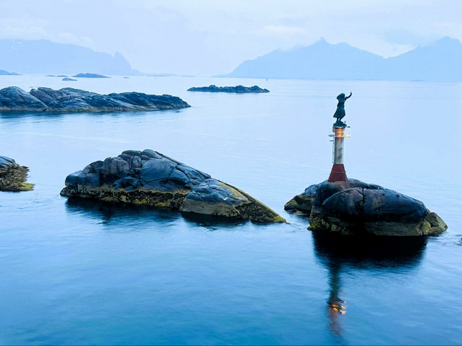 Statue of a fisherman's wife waving in the Lofoten harbor.