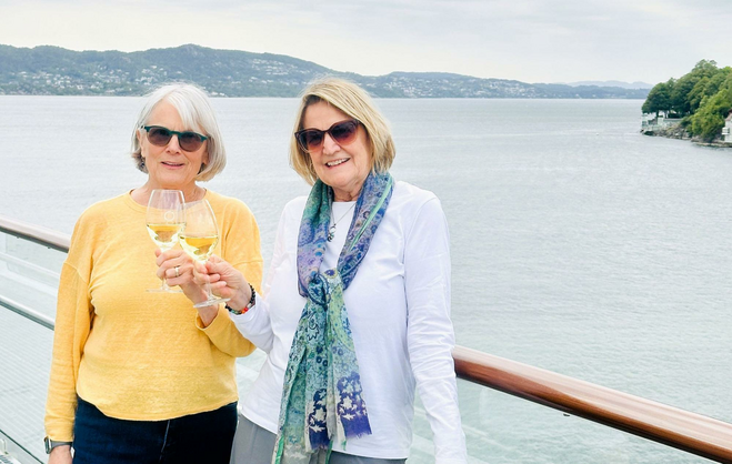 Author and her sister Linda toast glasses with wine on their sisters cruise.