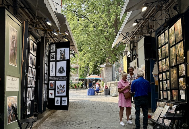 Couple interacting with an artist on Rue du Trésor near Château Frontenac, a dreamy Quebec City scene made for couples exploring together.