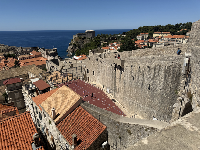 Looking down from atop Dubrovnik's city walls to a basketball court nestled against the base of the wall.