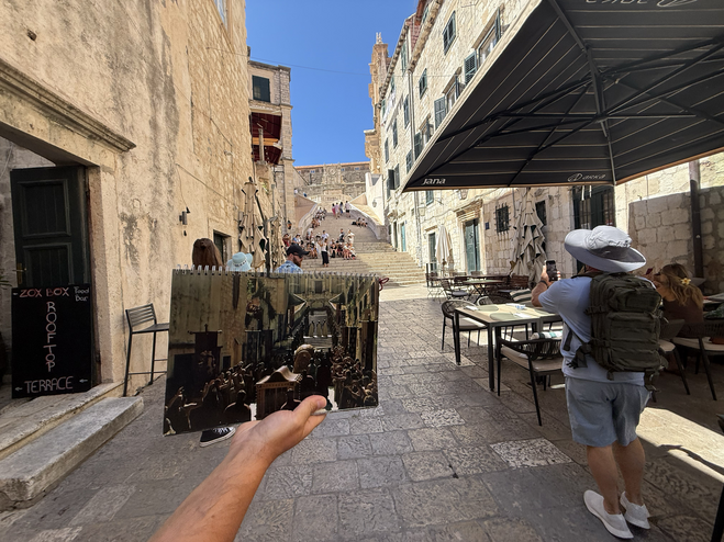 Game of Thrones Tour group walking through one of Dubrovnik's old medieval street with scene card from Game of Thrones in foreground.