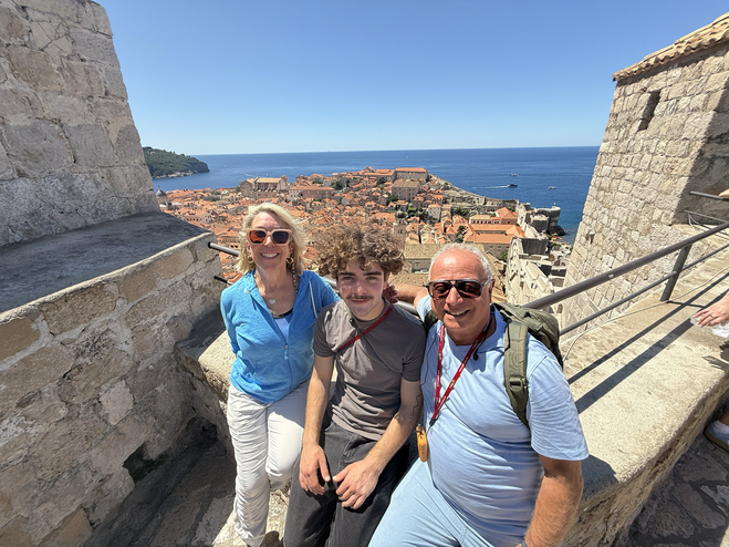 Family resting on a Game of Thrones Tour atop Dubrovnik's old city walls with city and coast in background.