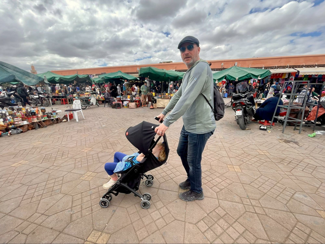 A man pushes a young girl in a stroller through a market in Marrakech, Morocco.
