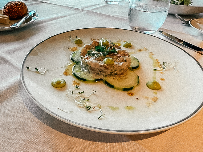 tuna and sauces on a bed of cucumbers on a lunch tablecloth