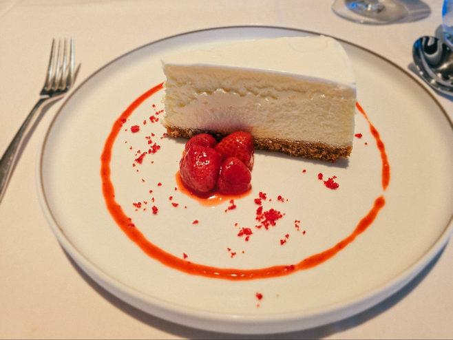 Slice of cheesecake on a plate with strawberries and strawberry sauce