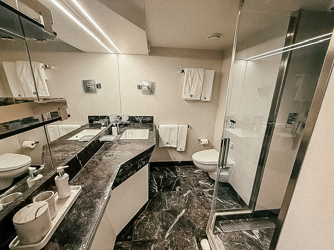 view of cruise ship stateroom from the bathroom door, showing black marble countertop and sink