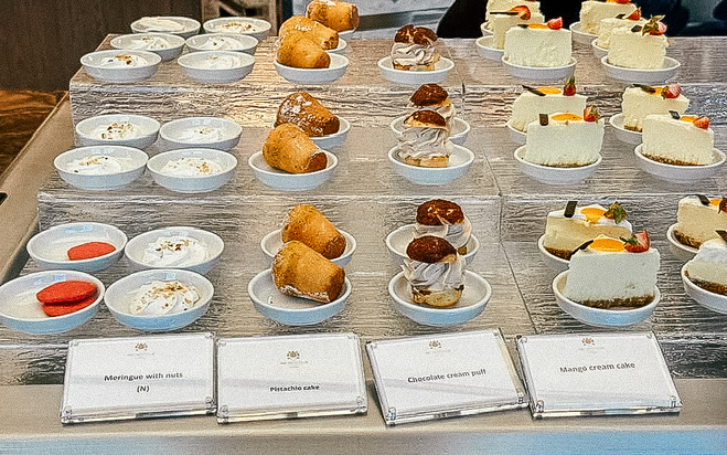 small pastries and desserts on a cruise ship buffet with signs describing what they are