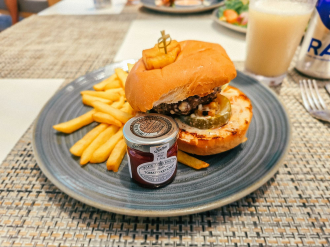 Hamburger on a plate with french fries and ketchup on a woven placemat