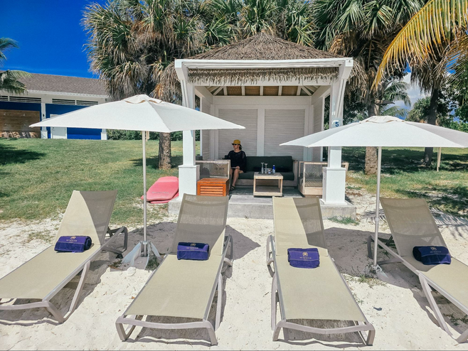 Beach cabana with woman sitting inside wearing a yellow hat