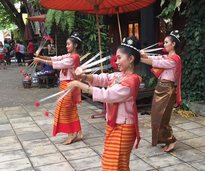 Three Thai dancers in pink shirts and orange skirts