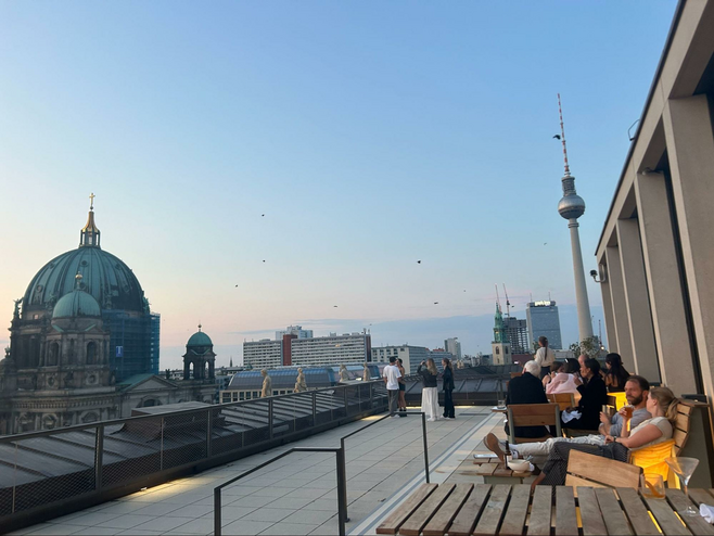 People sipping cocktails and enjoying the view of the Berlin skyline on the rooftop terrace of Baret, a restaurant on top of the Humboldt Forum.