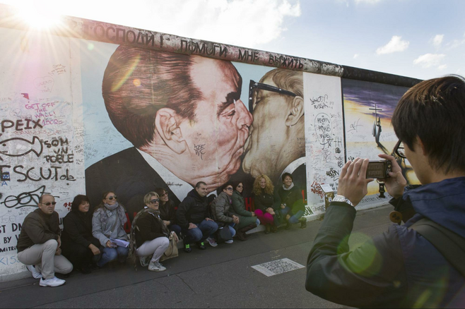 A tourist snaps a group shot in front of the famous mural at Berlin's East Side Gallery. 