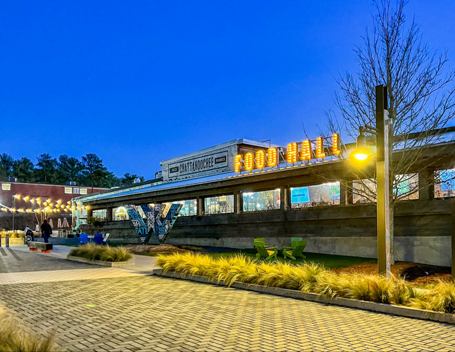 The long horizontal wooden building that houses Chattahoochee Food Works food hall at dusk
