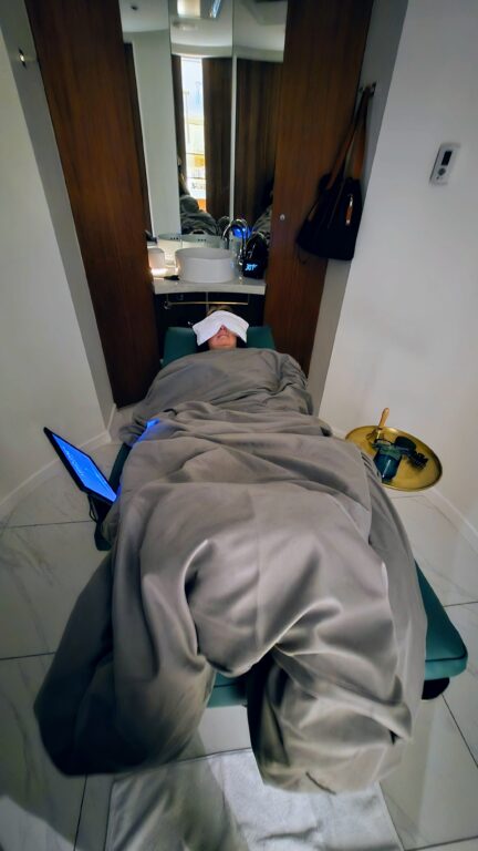 Woman laying under a weighted blanket during a Mind Sync treatment at the JW Spa at the JW Marriott Parq Vancouver