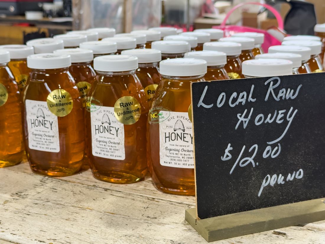 Close-up of labeled jars of unfiltered North Carolina honey on a market table Raleigh State Farmers Market.