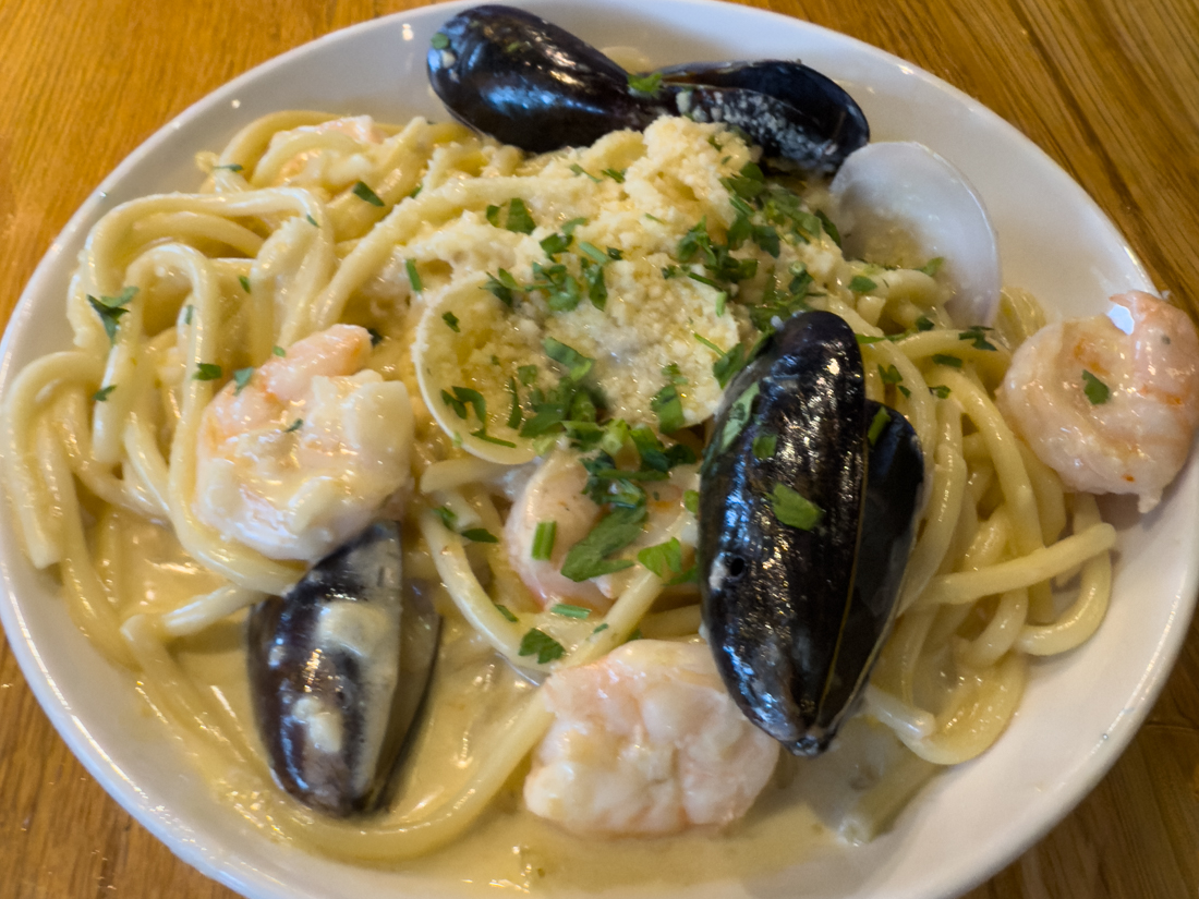 Overhead view of Irregardless Seafood Bucatini: thick pasta strands with shrimp and shellfish in a light sauce.