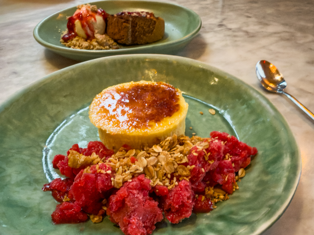 Plated desserts: embered crème brûlée with raspberry granita and fresh berries next to grilled pound cake with orange cream cheese ice cream, oat streusel, and strawberry compote.
