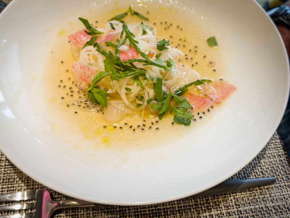 Delicate crudo small plate at Herons in The Umstead Hotel & Spa, thinly sliced fish with citrus, herbs, and microgreens.