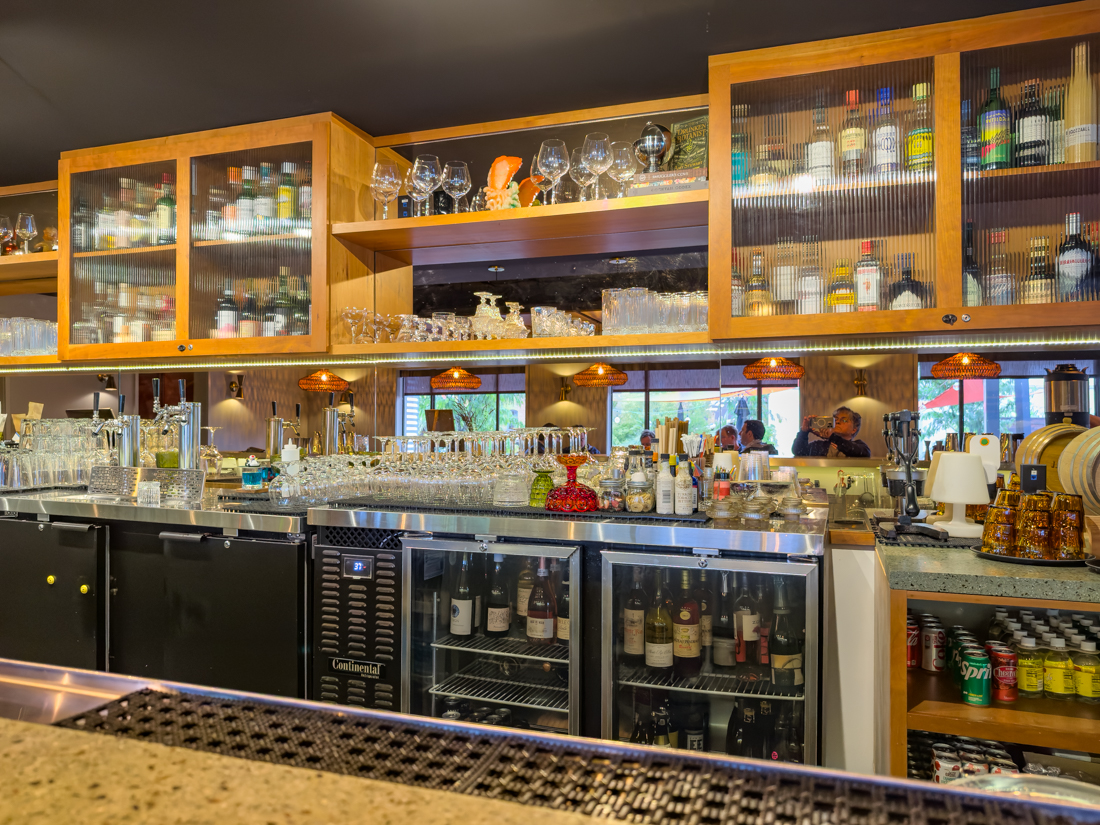 Interior of The Longleaf Hotel Lounge: backlit bar, neatly arranged spirits and wines, seating area, and a corner for casual games.