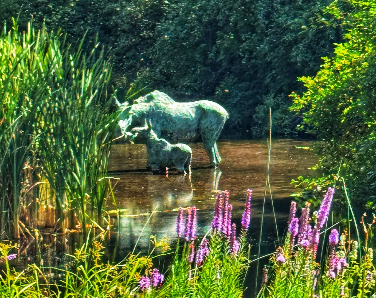 Flowers next to a pond wtih animal sculptures in Red Butte Garden in Salt Lake City.