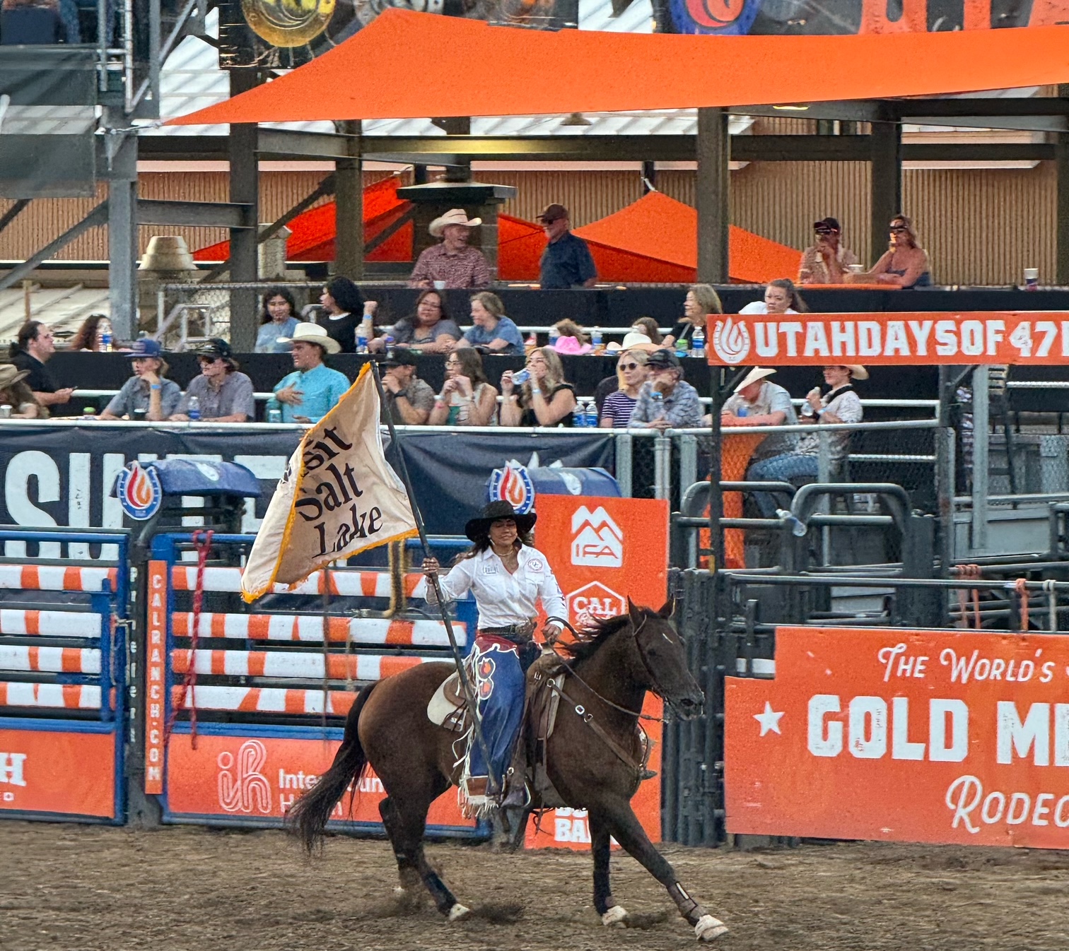 Woman riding a horse and carrying a flag at the Salt Lake City rodeo