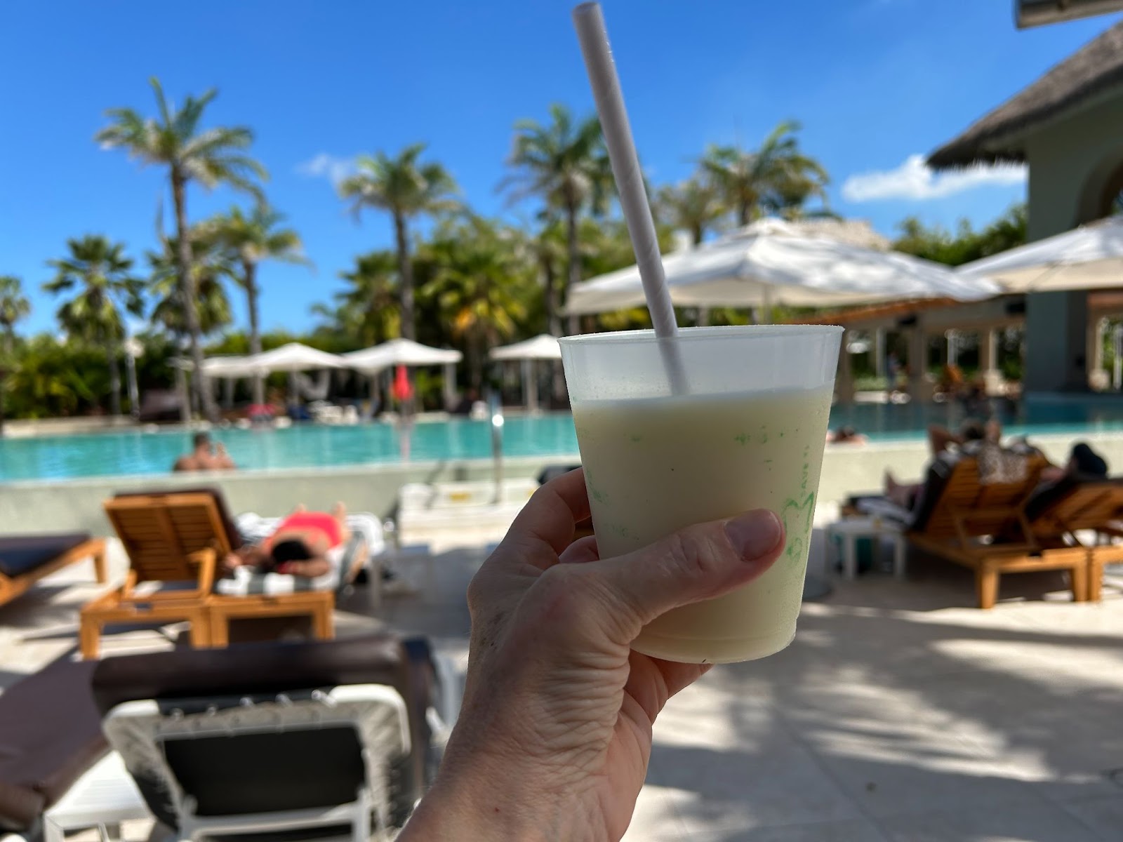 Hand holding a pina colada drink at a pool at the Hard Rock all inclusive resort in Punta Cana