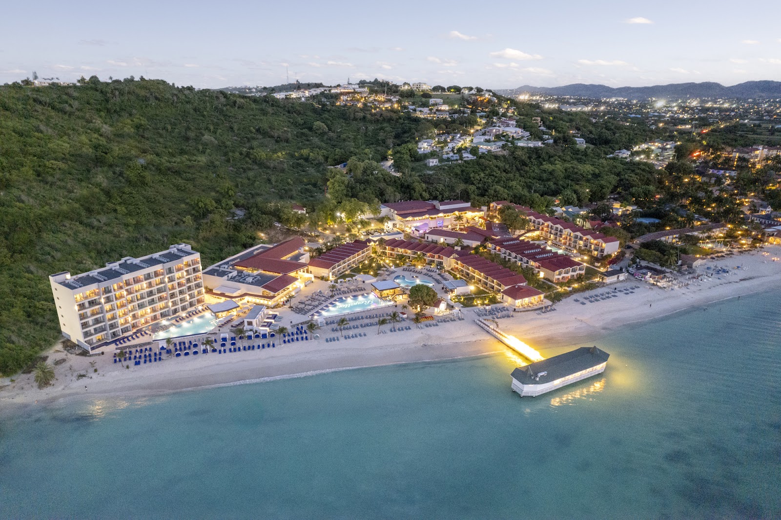 Royalton CHIC Antigua adults-only all-inclusive resort lit up from above with red roof resort and blue ocean