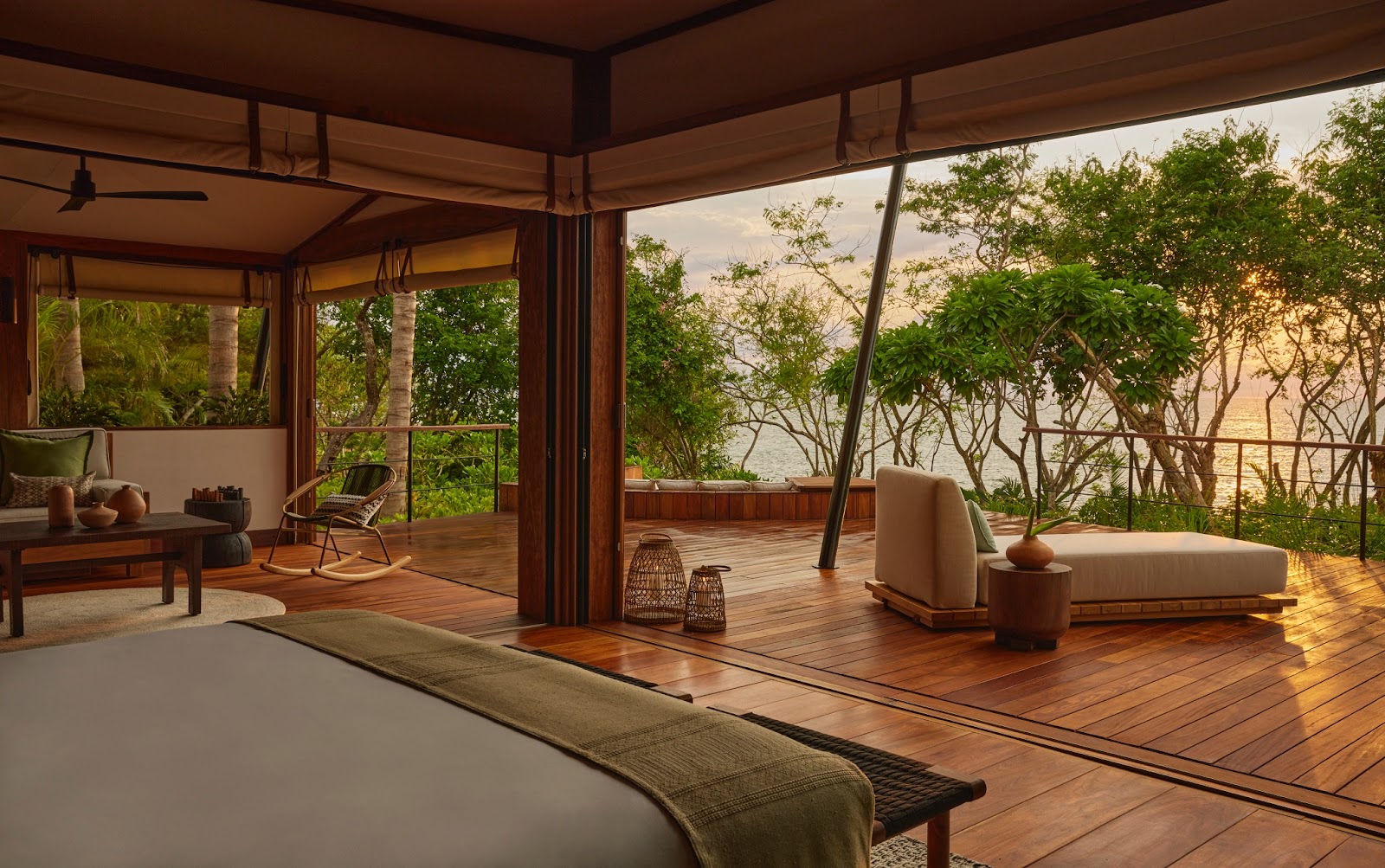 Brown wooden floors in open-air room at sunrise with green trees and water visible at Four Seasons Naviva adults-only all-inclusive resort
