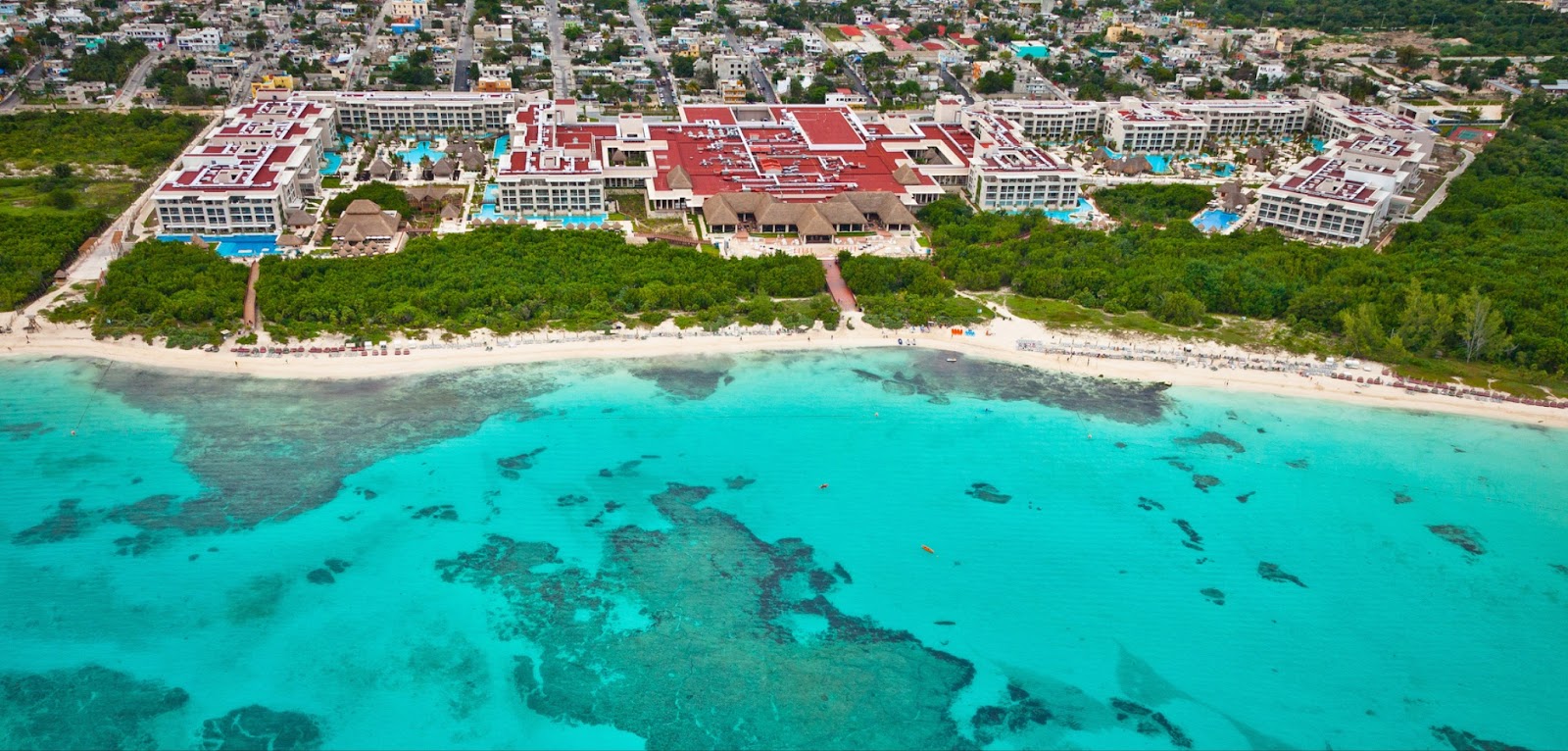 Blue/green ocean water, sand and resort with red roof at Paradisus La Perla adults-only all-inclusive resort Mexico
