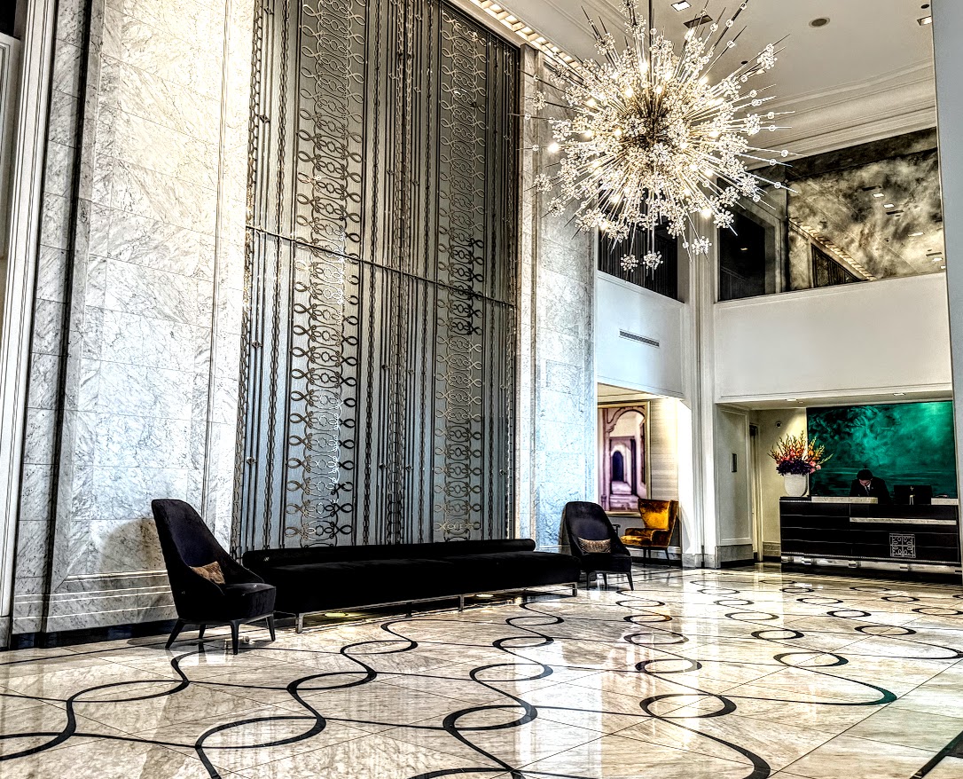 The black and white lobby of The Waldorf Astoria Chicago Hotel is elegantly adorned with a crystal chandalier.
