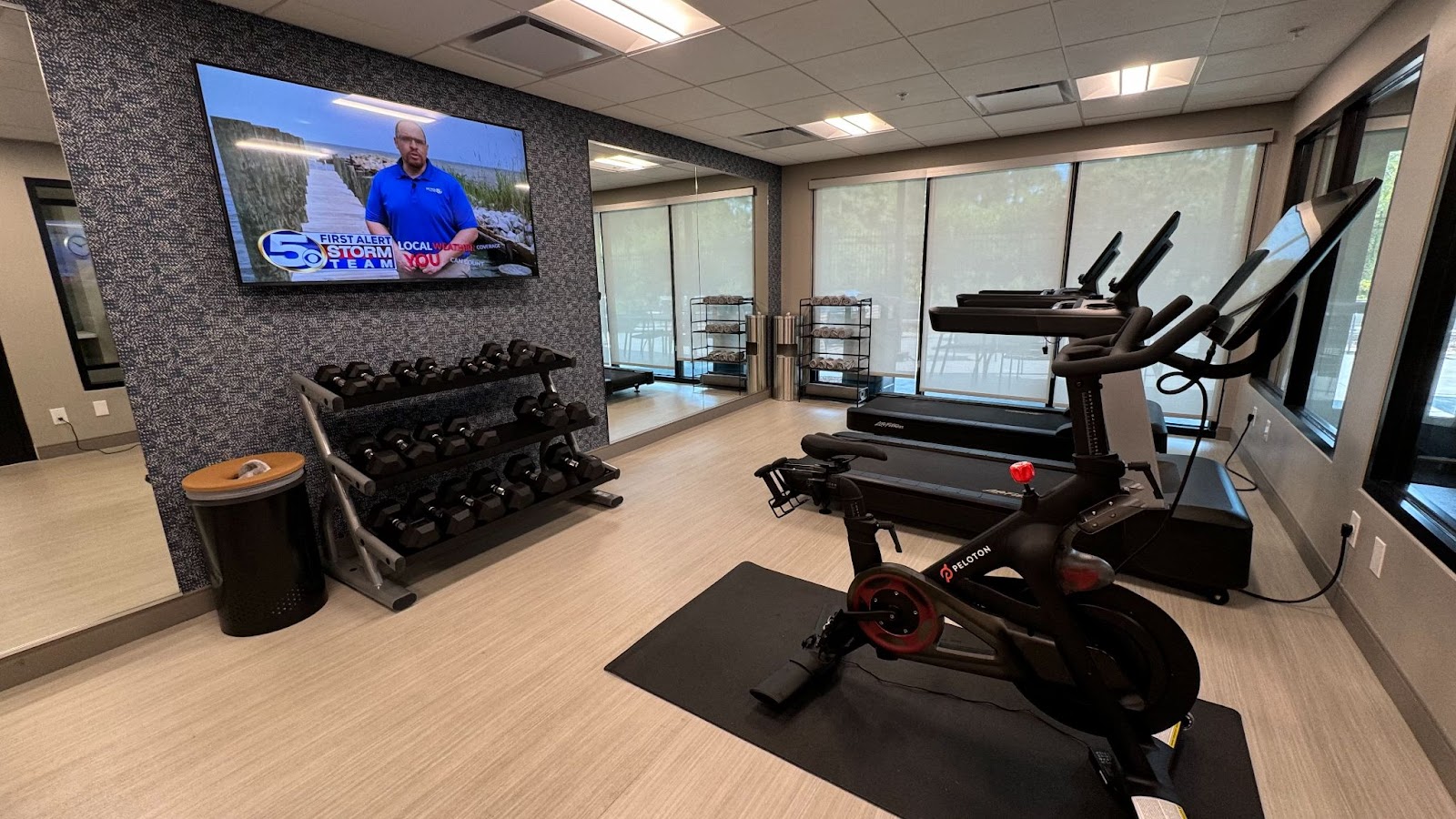 free weights, peloton and treadmill in an open room with a flat screen tv and mirrors on the wall at at Hyatt Studios Mobile Tillman's Corner