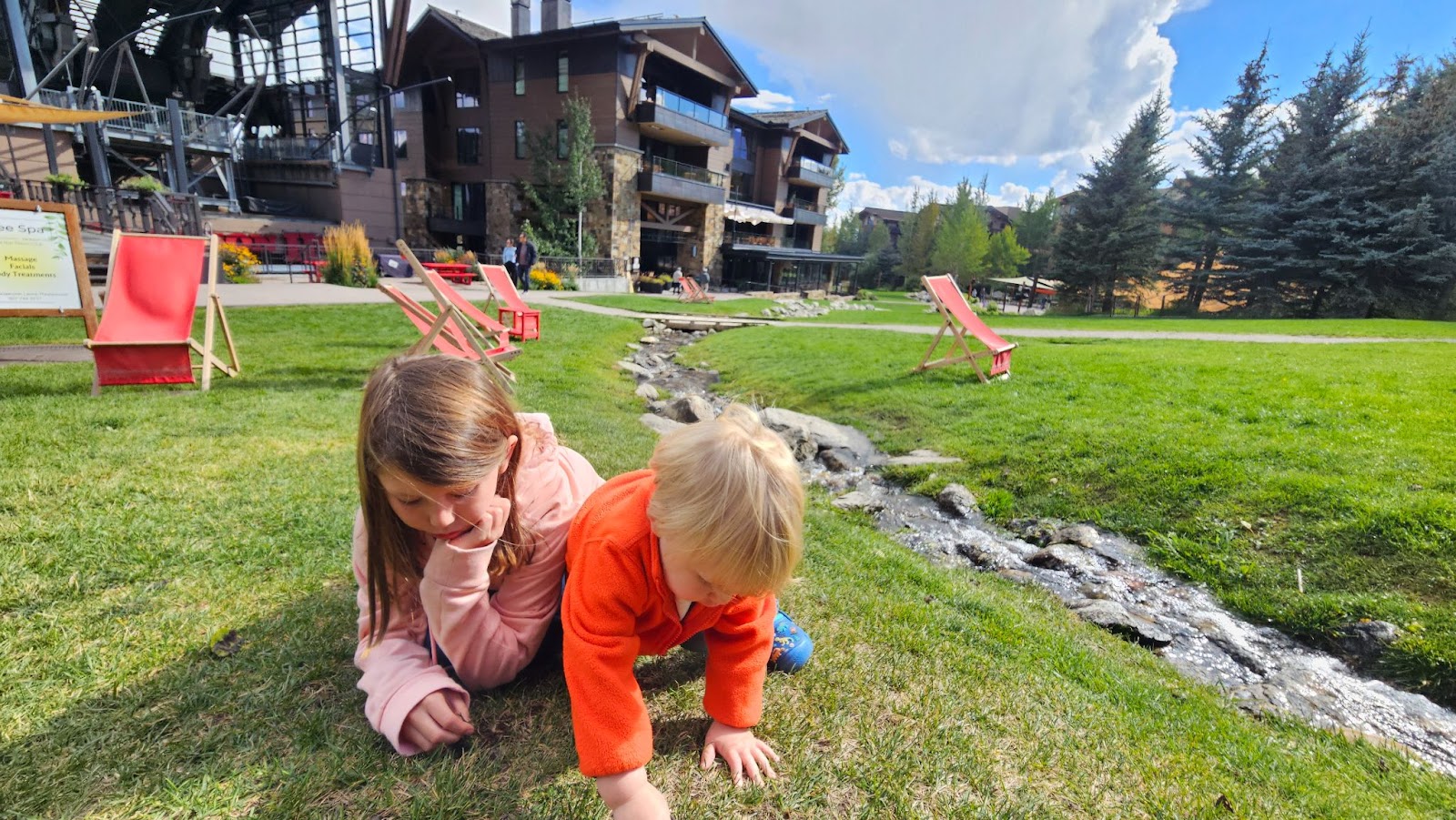 Two children playing on the lawn near a small creek in Teton Village Wyoming