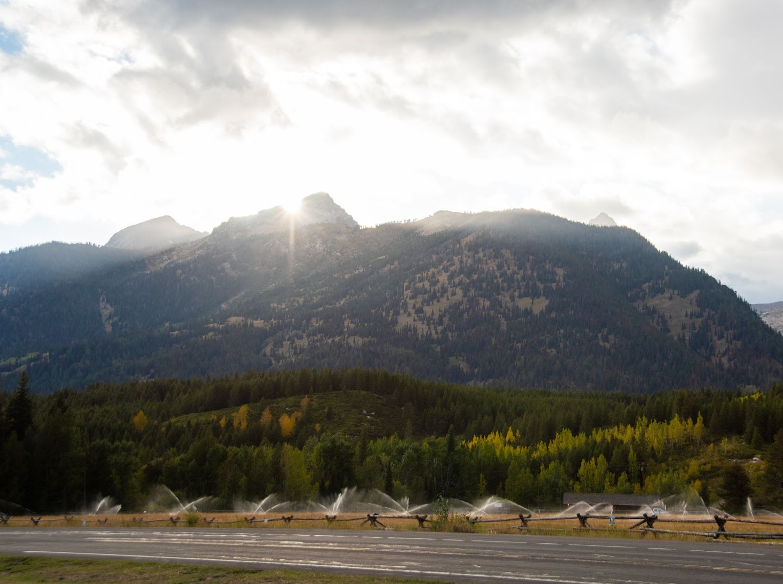 The sun peaking around the mountain tops before it begins to set in the Grand Teton Mountain range.