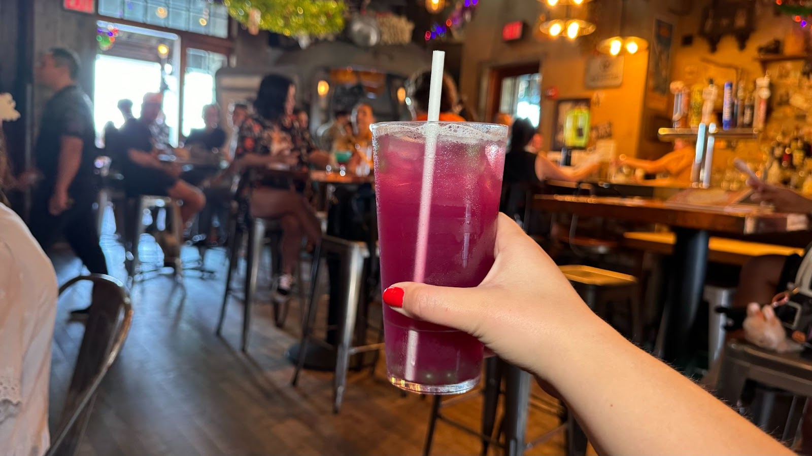 A hand holding a purple mocktail beverage at a Halloween bar in Orlando which is Jock Lindsey's Halloween Hangar Bar.