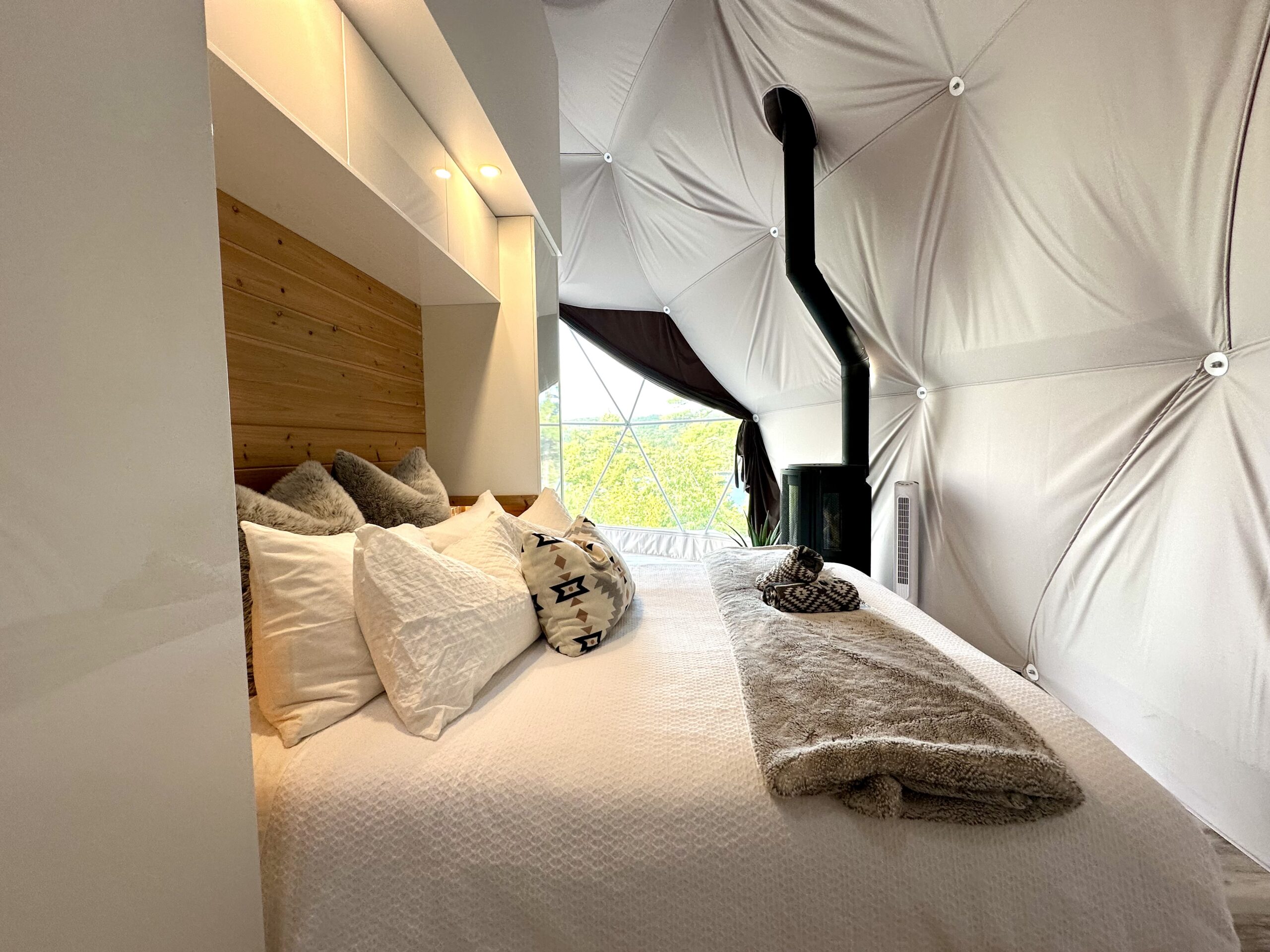 Luxury linens including a faux fur throw on a queen bed in a Nalu Retreat dome in Porters Lake, Nova Scotia.
