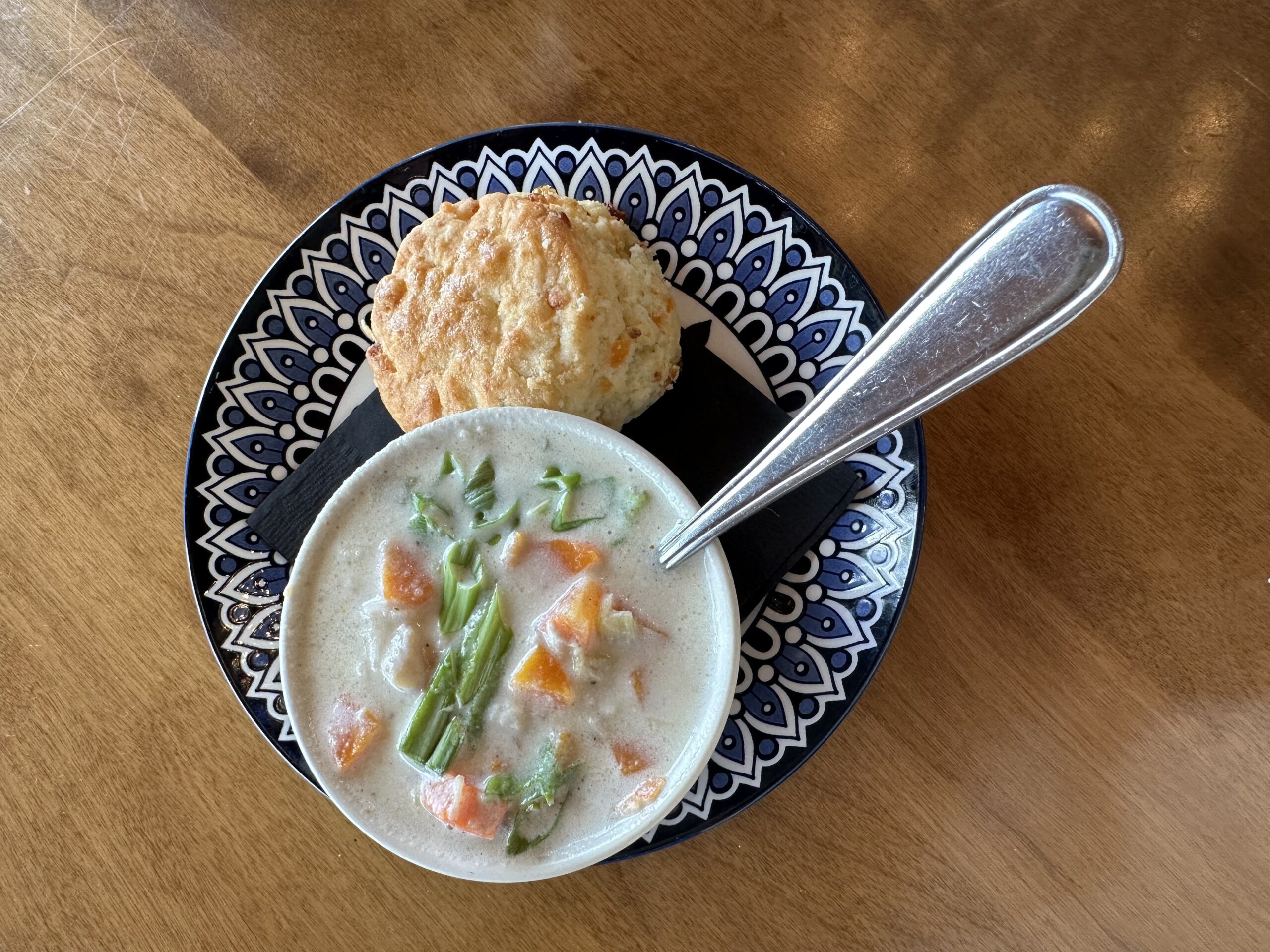 Veggies atop a chowder with a biscuit on a blue and white plate at Liscombe Lodge restaurant in Nova Scotia.