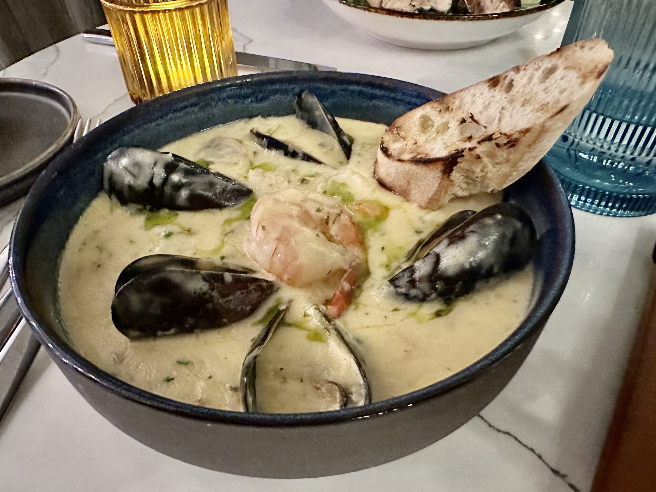 Bowl of chowder with mussels and shrimp with a toasted baguette slice at the Westin Nova Scotian Seaport Social in Halifax.