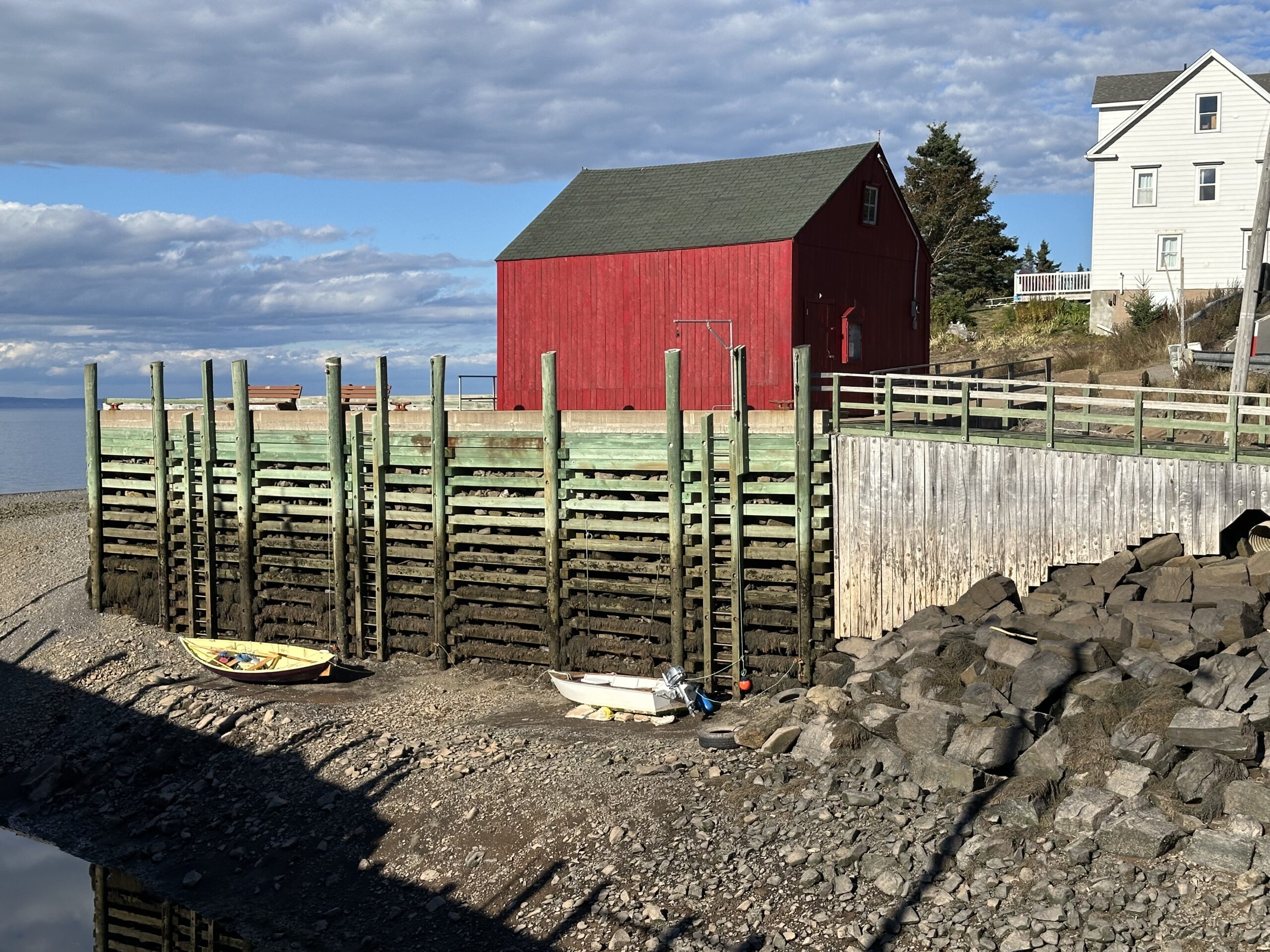 Two grounded row boats with red barn in background at low tide in the Bay of Fundy in Nova Scotia.