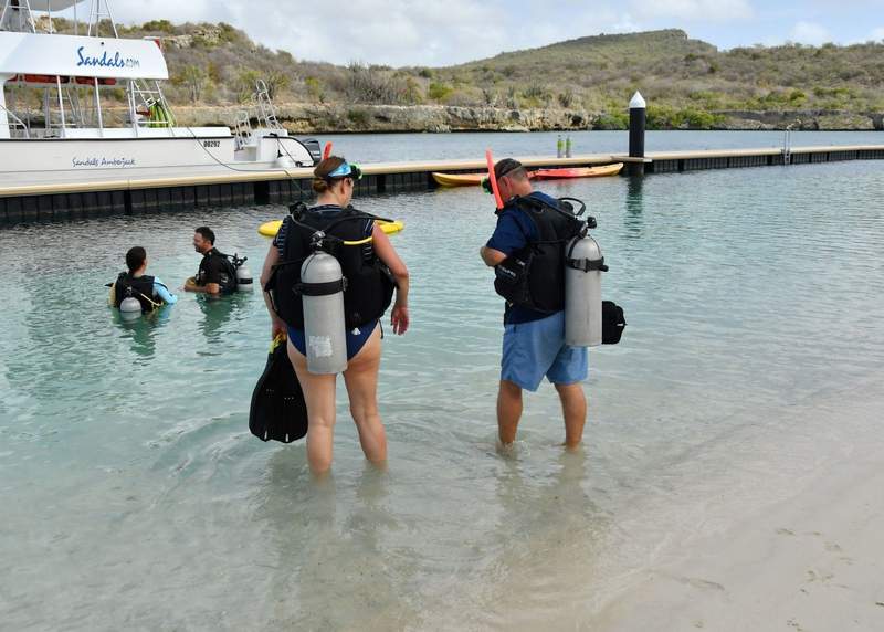 couple walking in the water with scuba tanks