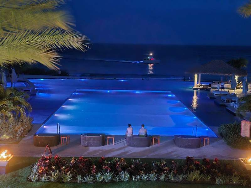 Couple sitting by a blue pool at night