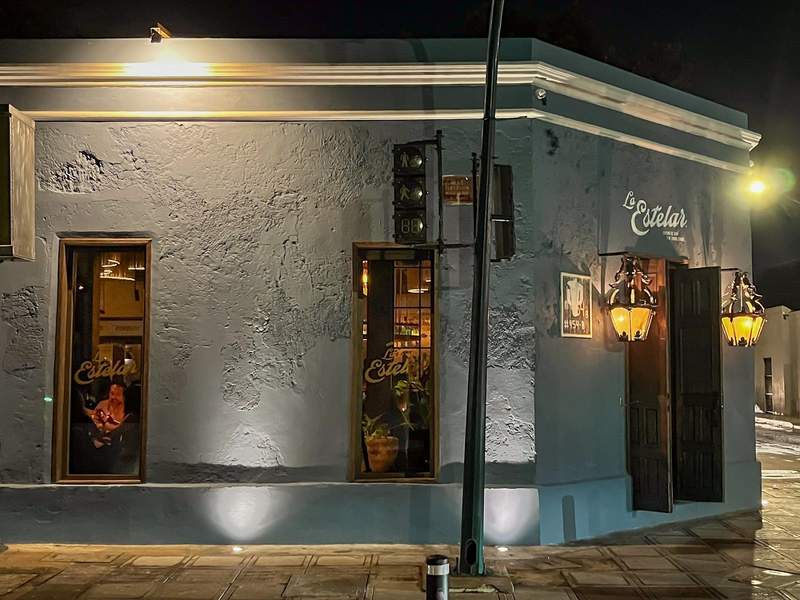 Facade of a colonial home turned restaurant, painted blue with two old-fashioned lamps above the front door.