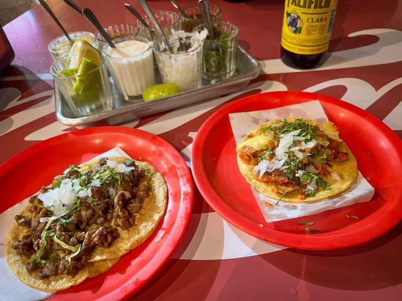 Meat tacos with chopped onions and cilantro, served on red plastic plates.
